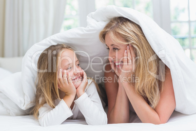 Mother and daughter looking at each other under the duvet