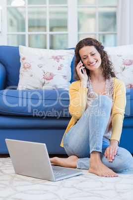 Pretty brunette sitting on the floor and speaking on the phone