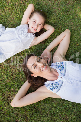 Mother and daughter lying on grass