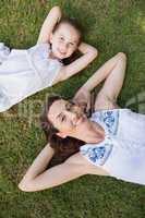 Mother and daughter lying on grass