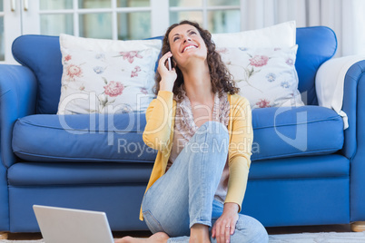 Pretty brunette sitting on the floor and speaking on the phone