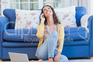 Pretty brunette sitting on the floor and speaking on the phone