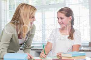 Happy mother helping daughter doing homework