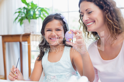 Happy mother and daughter painting easter eggs