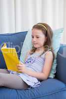 Little girl reading on couch