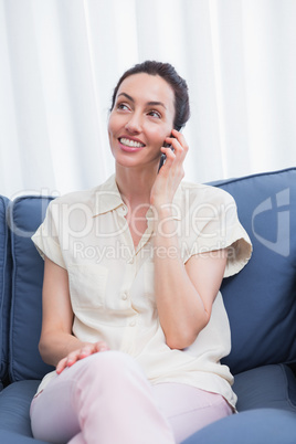 Casual brunette using phone on couch