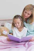 Happy mother and daughter reading a book