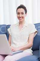 Casual brunette using laptop on couch