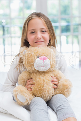 Happy little girl holding her teddy