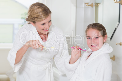 Happy mother and daughter brushing teeth together