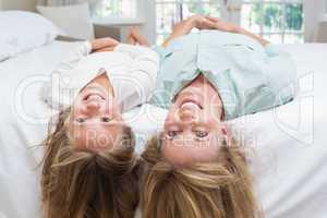 Mother and daughter looking at camera lying on the bed