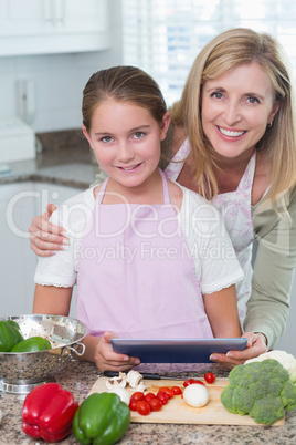 Mother and daughter cooking together with tablet pc