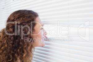 Curious woman looking through blinds