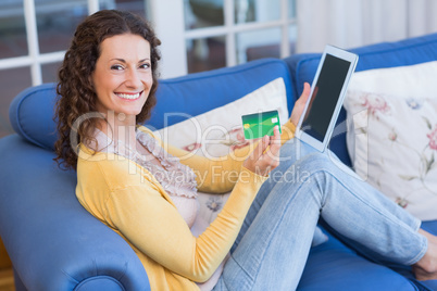 Pretty brunette relaxing on the couch with tablet