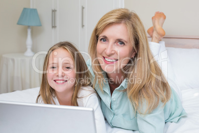 Happy mother and daughter using laptop