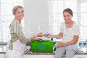 Mother and daughter putting bottles in recycling box
