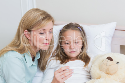 Mother measuring her daughters temperature