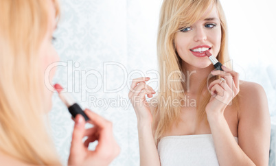 Smiling Blond Woman Applying Lipstick in Mirror