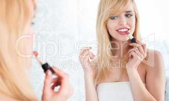 Smiling Blond Woman Applying Lipstick in Mirror
