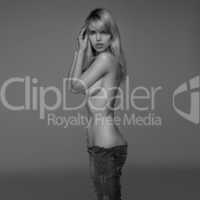Sexy Young Blond Woman Posing Shirtless in Studio Wearing Only Jeans and Cupping Breast in Hand, Studio Shot with Grey Background