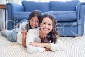 Happy mother and daughter lying on the floor