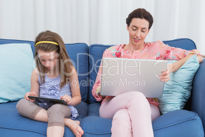 Mother and daughter using tablet and laptop