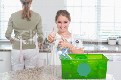 Little girl holding recycling bottles with thumbs up