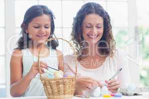Happy mother and daughter painting easter eggs