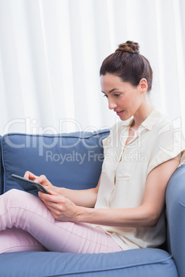 Casual brunette using tablet on couch