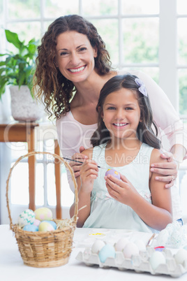 Happy mother and daughter painting easter eggs