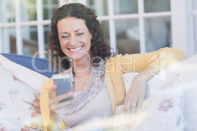 Pretty brunette relaxing on the couch with smartphone