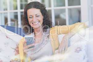 Pretty brunette relaxing on the couch with smartphone