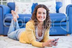 Pretty brunette lying on the floor and using smartphone