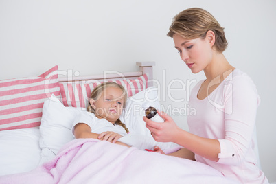 Mother about to give medicine to sick daughter
