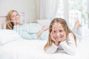 Little girl and mother looking at camera in the bed