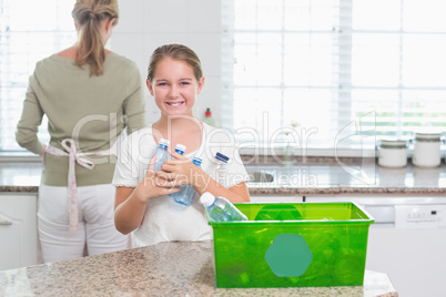 Happy little girl holding recycling bottles