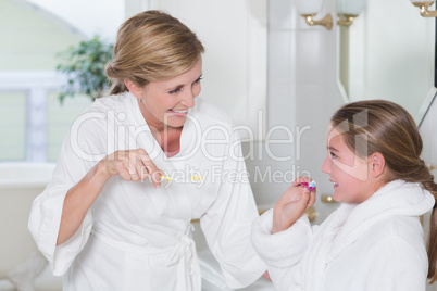 Happy mother and daughter brushing teeth together