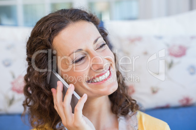 Pretty brunette sitting on the floor and speaking on the phone