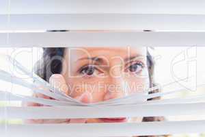 Curious woman looking through blinds