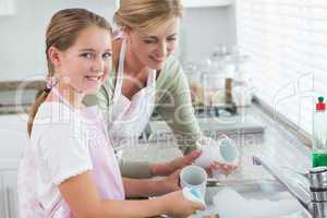 Happy mother and daughter washing up together