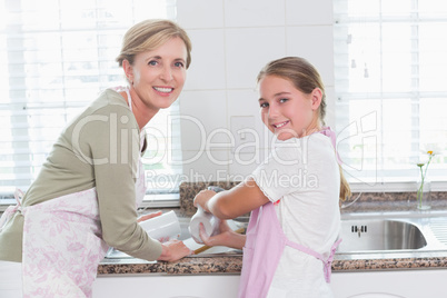 Happy mother and daughter washing up together