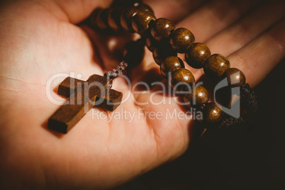 Hand holding wooden rosary beads