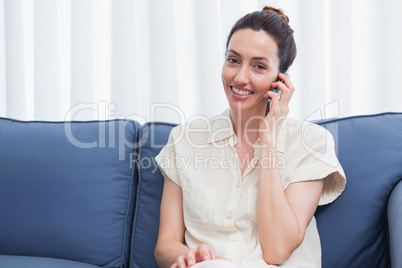 Casual brunette making phone call on couch