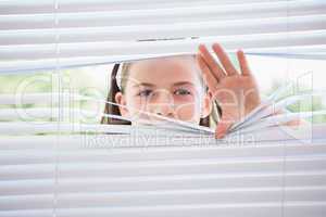 Little girl peeking through blinds