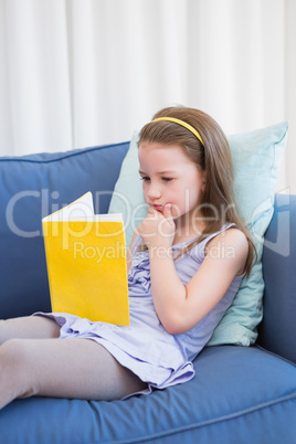 Little girl reading on couch