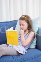 Little girl reading on couch