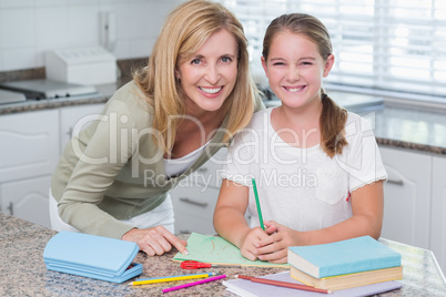 Happy mother helping daughter doing homework