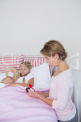 Mother about to give medicine to sick daughter