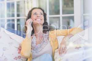 Pretty brunette relaxing on the couch and speaking on the phone