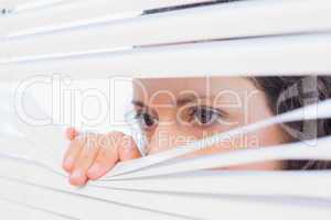 Curious woman looking through blinds